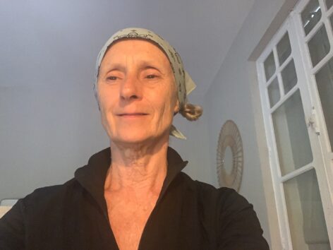 Selfie of K.J. Holmes: Woman with blue handkerchief on her head with a slight smile.