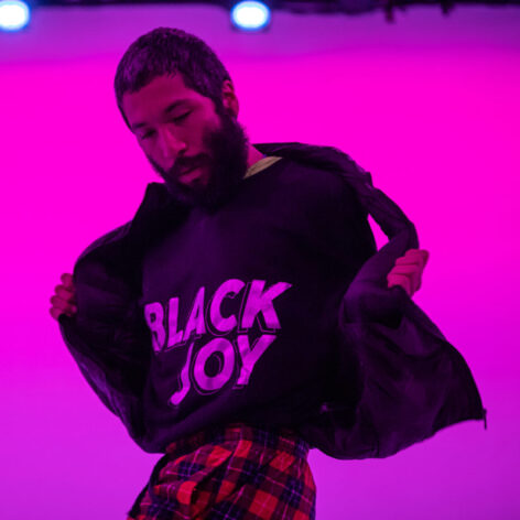 Estrellx holds their jacket open showing off a black t-shirt with white text that reads