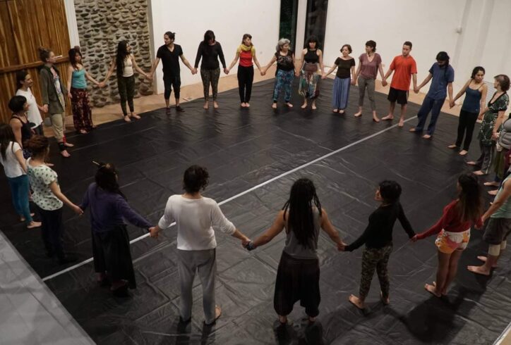 A group of people standing in a circle, holding hands. Photo courtesy of Luce Mahler.