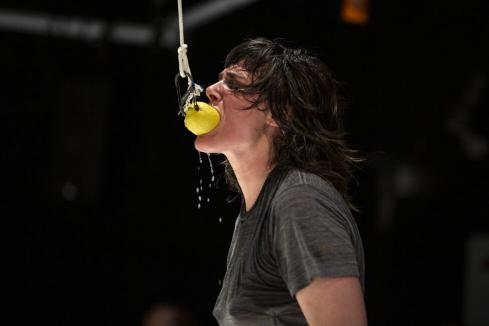 Dancer performing, biting down on a lemon in her mouth.