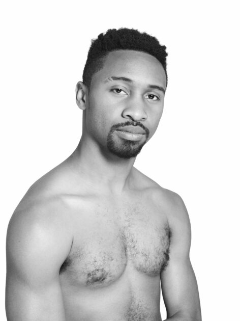 A black and white portrait of Johnnie Cruise Mercer. He looks at the camera slightly leaning to the right shirtless.