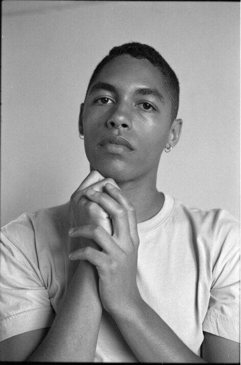 Weidie, Black and white photo of Maxi holding their hands under their chin. Photo by Spencer James.
