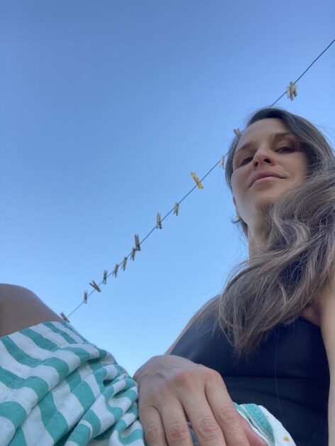 Vanessa is wearing a tank top and a striped skirt. A rope line is in the back, against an open clear sky.