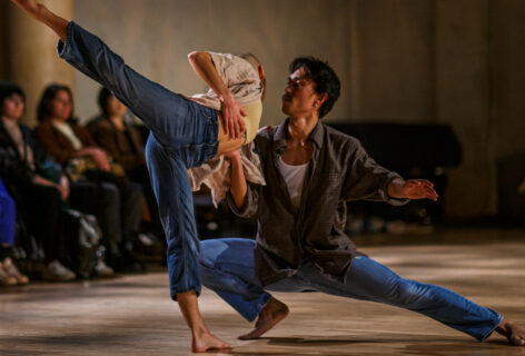 KAŌS Dance Collective performing for Movement Research at the Judson Church. One dancer is in a deep lunge supporting another dancer who leans towards them for support while performing an arabesque. Photo by Rachel Keane.