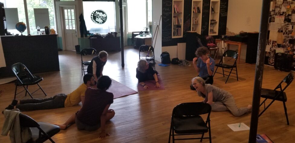 Leah and Annie alongside other people sitting comfortable on the floor in a circle during the Culture Mill PD LAb.