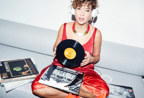 Shirine Saad is wearing a red outfit and holding a record and headphones. Photo by Eva Sakellarides.