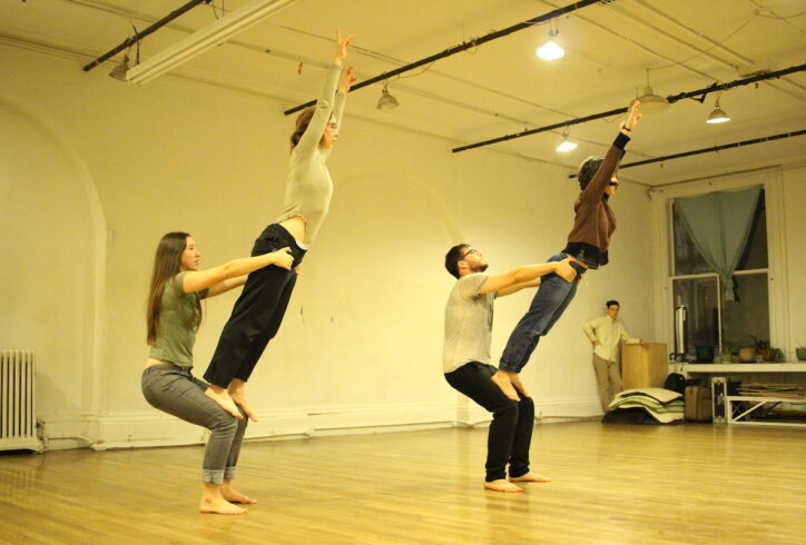 From the MR Archives, 2016 Open Performance: Artist unknown. Two Dancers stand on the lap of two other dancers, they are holding them at the hip while the standing dancers lean slightly forward.