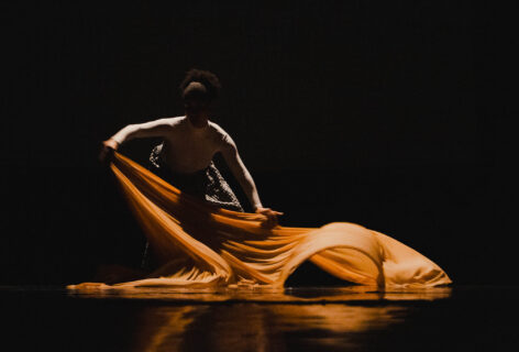 Dancer utilizing fabric through movement under shadow and low lit stage. Photo by Jonathan Maier.