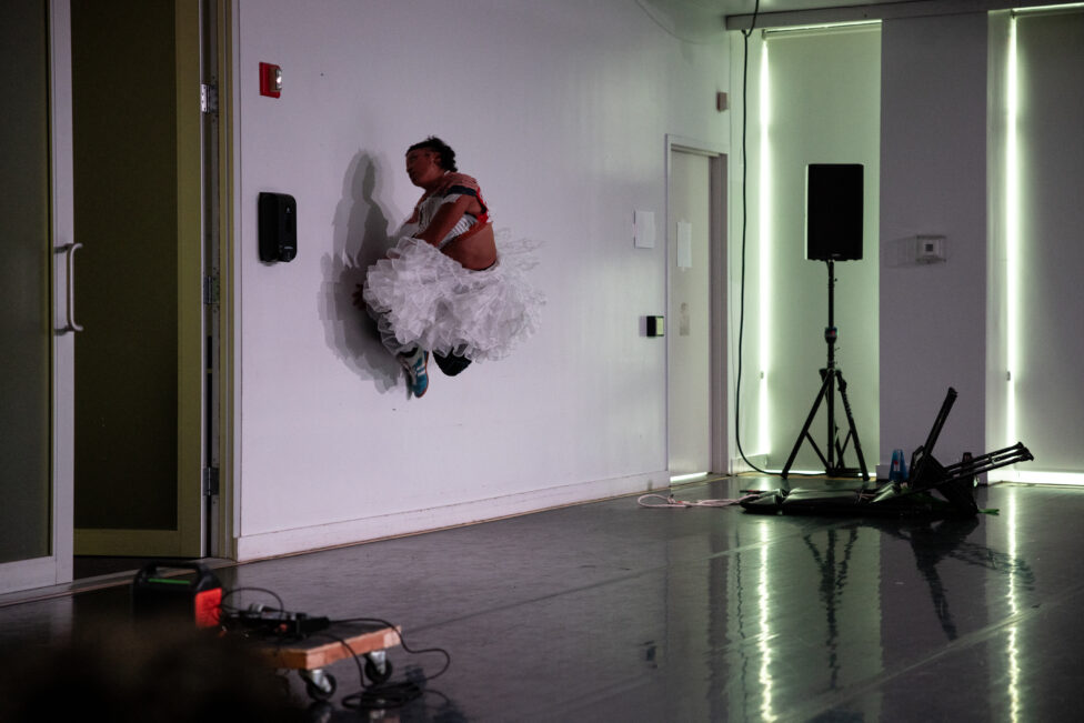 Legs folded underneath her, Symara is pressed against a white wall, appearing to defy gravity. Image by Maria Baranova.