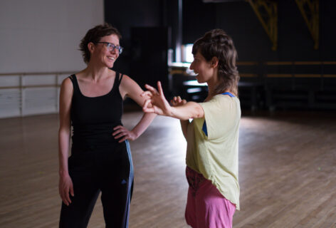 Tatyana gestures energetically with her arms and fingers, her mouth opened, as a student looks on. Photo by Anna M. Maynard.