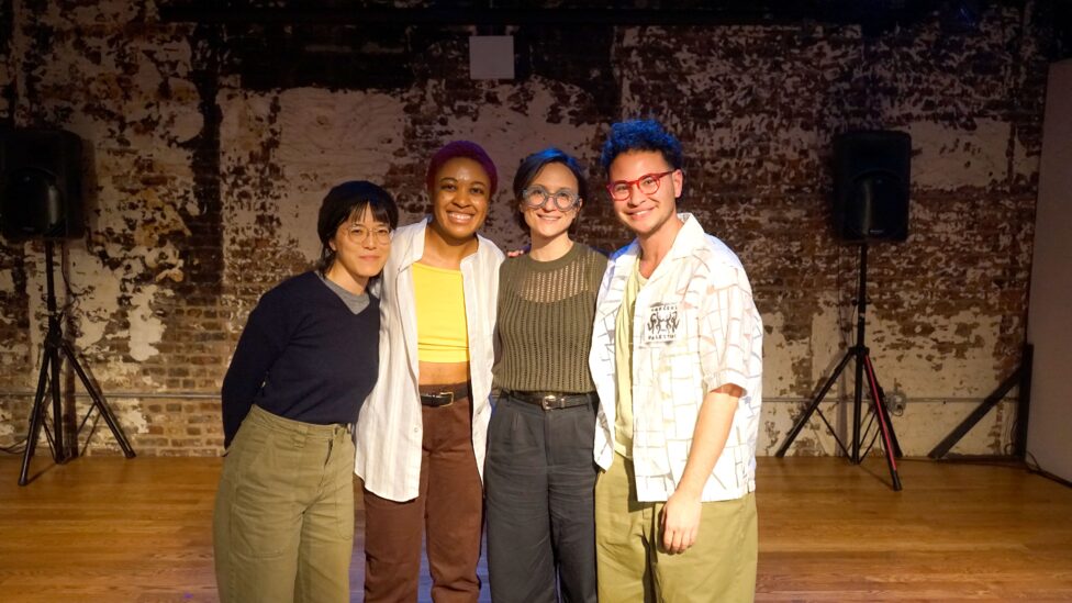 Jamie (far left), Maya Simone, Elizabeth, and zavé (far right) gather together and smile for the camera. Jamie is an Asian person with straight black hair and bangs, wearing a black beret, round metal glasses, a navy sweater over a grey shirt and green pants. Maya Simone is a Black person with short red dyed hair, wearing a yellow tank top and white open button down and red pants. Elizabeth is a white woman with short brown straight hair wearing chunky blue round glasses, green knit top over a black tank top, black slacks and a belt. zavé is a mixed Asian person with short curly brown hair wearing pink glasses, green tank top and pants and an open white button down teeshirt with a print pinned to it that says “Dancers for Palestine” with black figures dancing. Photo by Cinthia Chen.