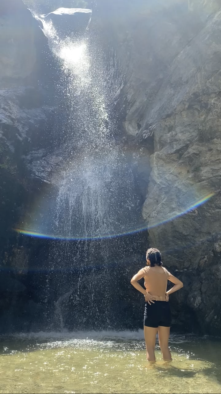 Lindsey standing in the Eaton Canyon Waterfall, under a rainbow. 