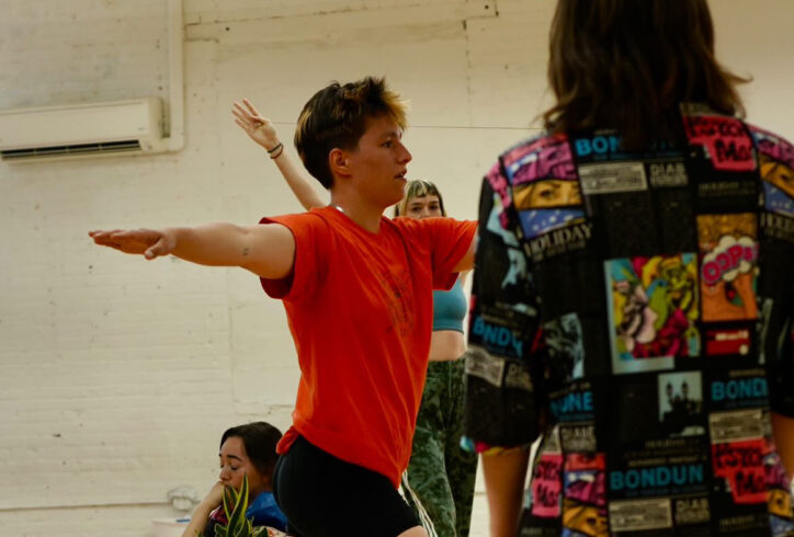 Juliana F May's class; a dancer with their arms out in T shape and one's back toward the lens, and another crouched behind. Photo by Amelia Golden