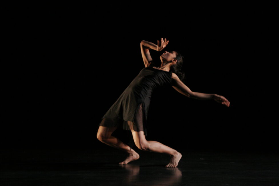 Preeti Vasudevan in Waiting for the Fifth Arrow. Medium-toned woman leans back with one hand near her face and one hand pointed backwards. Photo credit: Steven Shrieber