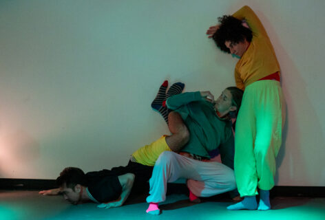 Three dancers in different poses leaning on a wall. Photo by Kate Barber of JAM, Junction Arts & Media