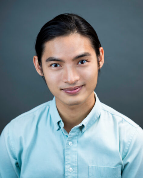 Portrait photo of a smiling Asian male wearing a bright teal button-up. Photo by Adam Rose.