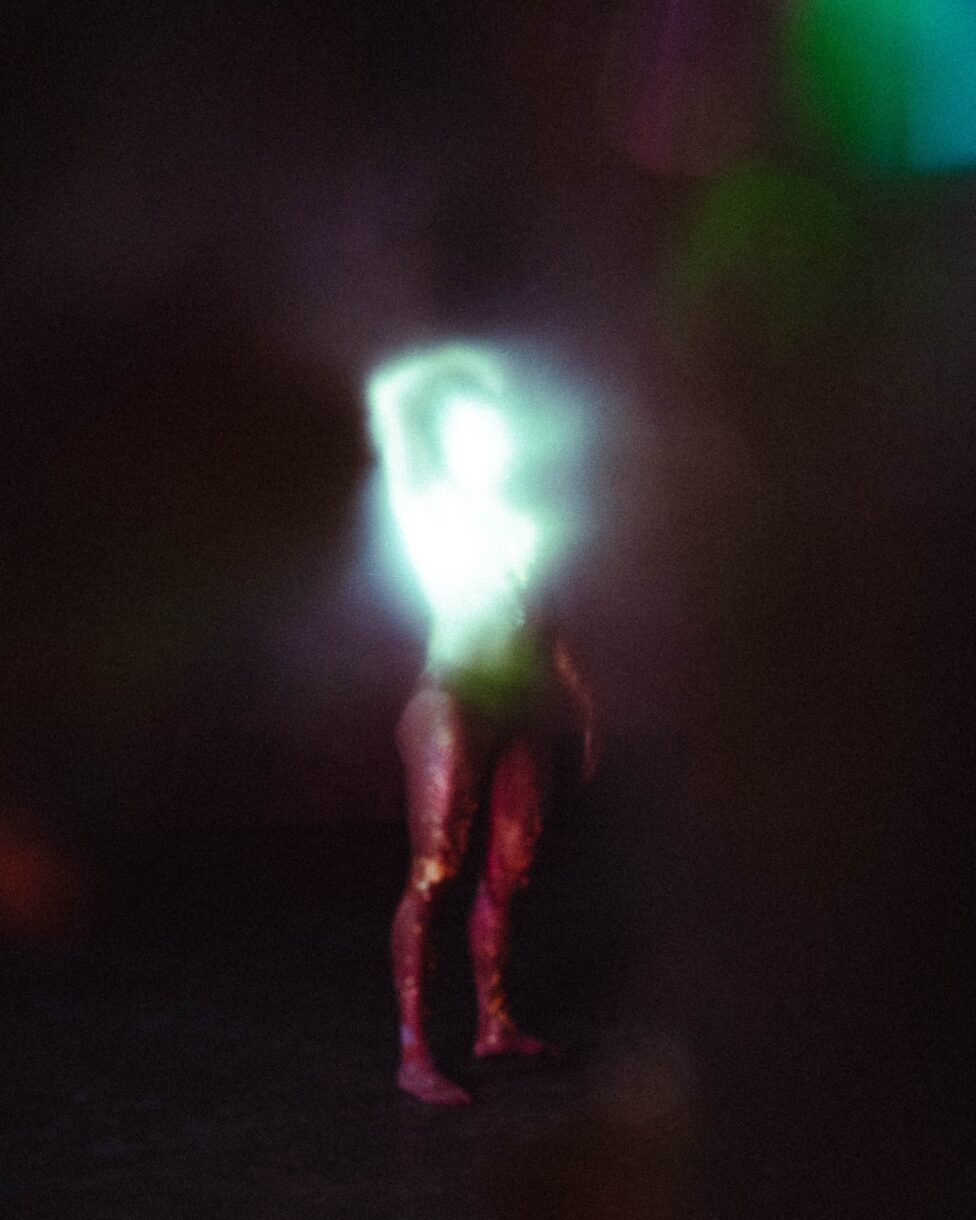  Riven is a distant and blurry figure. Gold residue trails down his legs, and his torso reflects and diffuses into a flare of light.
Photo credit: Parawis Jiamchaotpattanakul